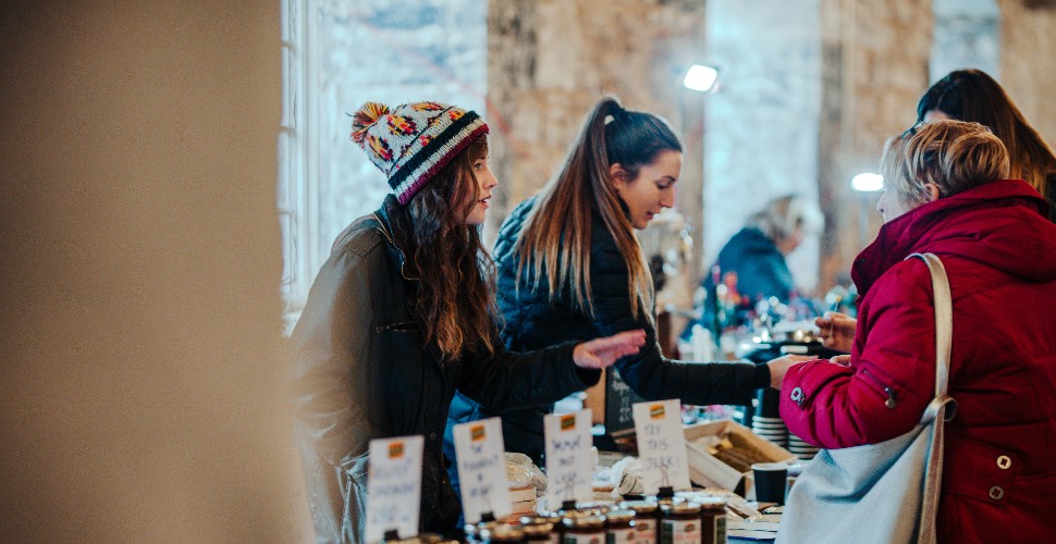 Shoppers browsing stands at Royal William Yard Christmas Market inside the Melville building